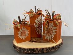 three small orange boxes with sunflowers on them are sitting on a tree stump