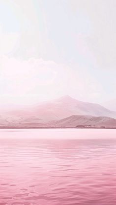 a large body of water with mountains in the background and pink hues on the water