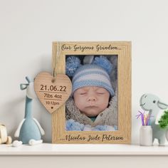 a wooden frame with a baby's birth photo and a heart hanging from it