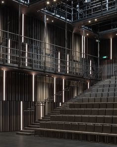 an empty auditorium with rows of seats and railings on each side, lit by lights