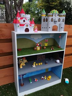 a toy castle is on top of a bookcase in the grass near a fence