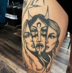 a woman's leg with tattoos on it and two women in the middle, one has