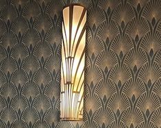 an art deco wall lamp hanging on the side of a wall next to a sink