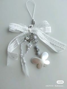 an ornament hanging from a white ribbon with beads and bows attached to it