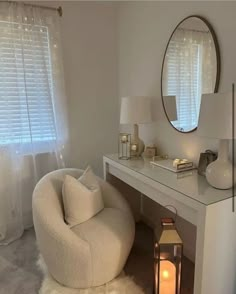 a white chair sitting next to a table with a lamp on it and a mirror above it