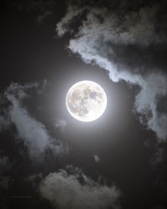 the full moon is seen through some clouds