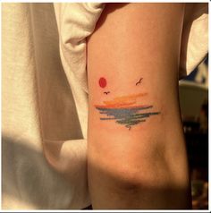 a woman's arm with a small watercolor sunset tattoo on her left arm