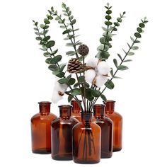 four brown glass vases filled with flowers and greenery next to each other on a white background