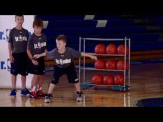 three young boys standing in front of basketballs on a court with one holding the ball