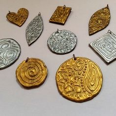 several different types of gold and silver pendants on a white surface with black border