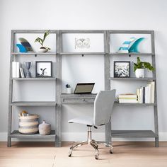 a desk with a laptop on it in front of a book shelf filled with books