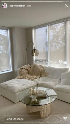 a living room filled with white furniture and windows covered in shades of light from the outside