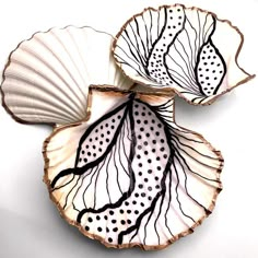 two decorative plates with black and white designs on them, one is shaped like a leaf