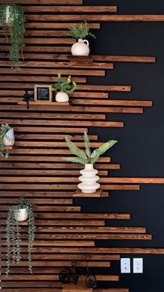 the wall is made out of wooden slats and has plants in vases on it