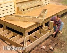 a man kneeling down next to a wooden deck with drawers in it and another person working on the deck