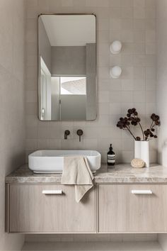 a white sink sitting next to a mirror on top of a wooden cabinet in a bathroom