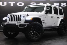 a white jeep parked in front of a auto sales sign