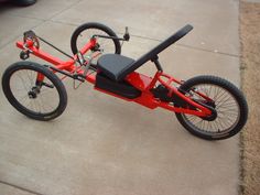 a red bike with two seats on the front and rear wheels is parked in a driveway