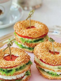 mini sandwiches with cheese, lettuce and tomato on them sitting on a plate