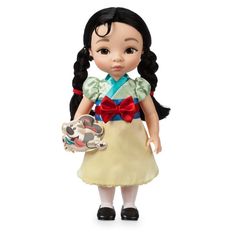 the doll is wearing a dress and holding a toy in one hand, with a red bow on it's head