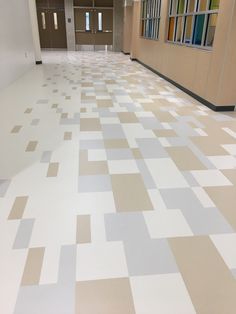 an empty hallway with white and tan tiles on the floor is pictured in this image