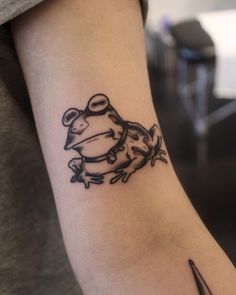 a small frog tattoo on the arm