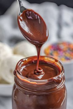 a spoon full of melted chocolate on top of a jar