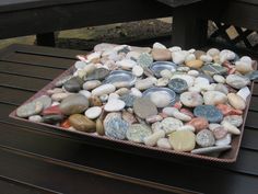 a tray filled with lots of rocks on top of a wooden table next to a bench