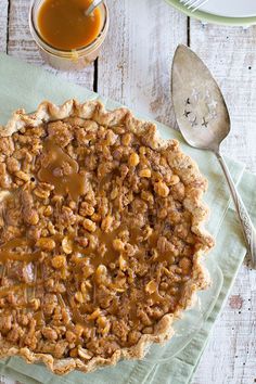 a pie sitting on top of a green napkin next to a cup of coffee and spoon