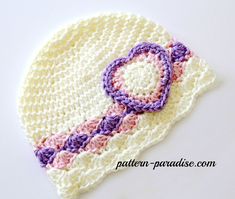 a crocheted hat with a purple and white circle on it's side