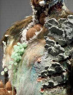 an art work with rocks and pebbles on it's surface, including green beads