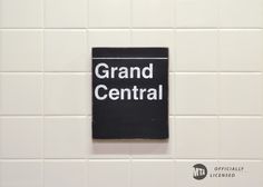 a black and white sign that reads grand central on it's side in a bathroom