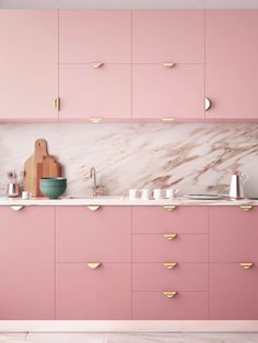 a kitchen with pink cabinets and white counter tops, gold accents on the backsplash