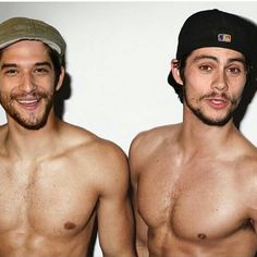 two shirtless men standing next to each other in front of a white wall and smiling