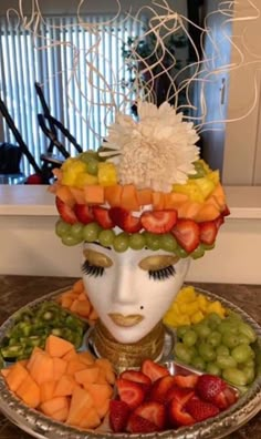 a woman's face made out of fruit and vegetables on top of a plate