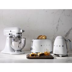 three different types of kitchen appliances on a white counter with marble back splash behind them