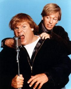 two men standing next to each other holding a microphone in front of their face and making faces