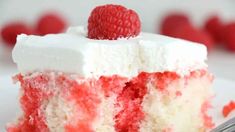 a close up of a piece of cake on a plate with a fork and raspberry