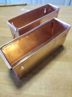 two metal containers sitting on top of a wooden table