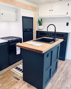 a kitchen with an island and black appliances in the center, along with a rug on the floor