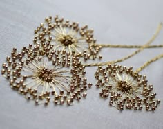 two golden dandelions on a white table cloth with gold thread and beading