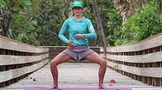 a woman standing on a yoga mat in the middle of a bridge with her hands behind her back