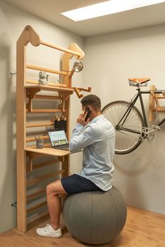 a man sitting on top of a ball while talking on a cell phone