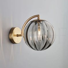 a light that is on the wall next to a white wall with a glass ball