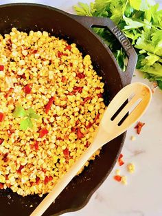 a skillet filled with corn next to lettuce