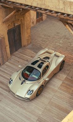 a silver sports car parked on top of a wooden floor next to a building under construction