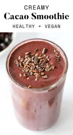 a smoothie in a glass with granola on top and text overlay that reads creamy cacao smoothie healthy + vega