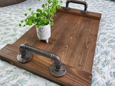 a potted plant sitting on top of a wooden tray next to an iron pipe