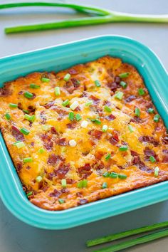 a casserole dish with bacon, cheese and green onions in it next to chopsticks