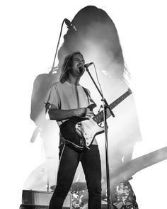 a man standing on top of a stage with a guitar in front of his face